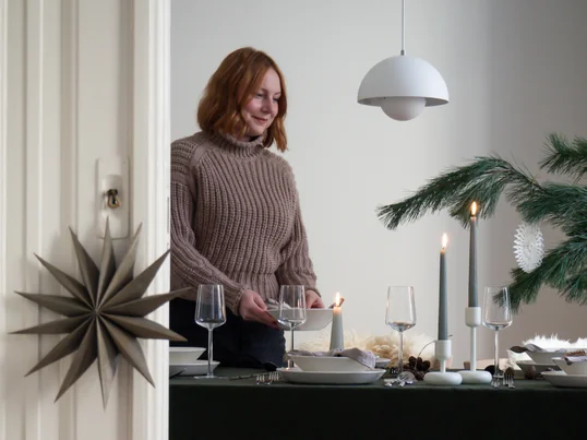 Die Nappula Kerzenständer von Iittala in der Ambienteansicht: Die weissen Kerzenständer und die Essence Trinkgläser kommen auf der grünen Tischdecke hervorragend zur Geltung.