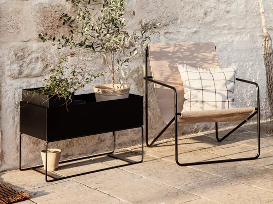 Der Desert Chair von ferm Living in der Ambienteansicht: Der filigrane Stuhl schafft zusammen mit der Plant Box eine gemütliche Atmosphäre zum Entspannen auf der Terrasse.