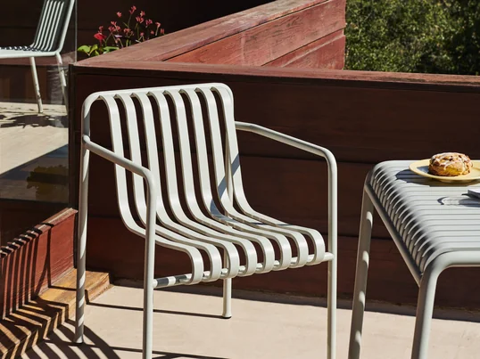 Der Palissade Dining Armchair von Hay in Hellgrau lädt mit seinen Armlehnen zum Sitzen und Verweilen im Aussenbereich zum Beispiel auf der Dachterrasse ein.