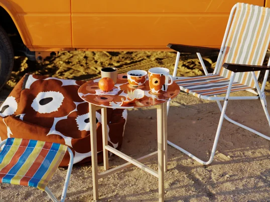 Die Oiva Unikko Schale und der Oiva Unikko Becher mit Henkel von Maija Isola für Marimekko überzeugen durch die warmen Farben mit dem floralen Muster.