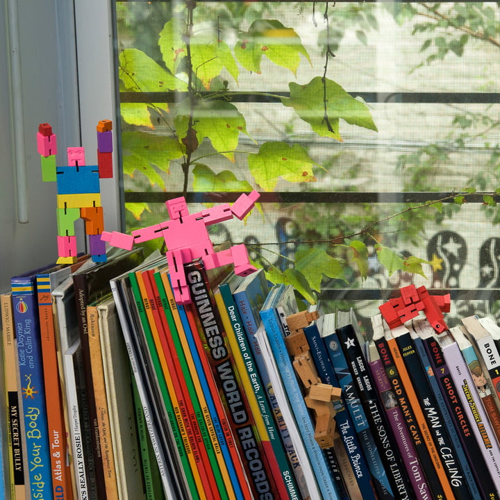 Der Cubebot von Areaware klettert auf Bücherstapeln