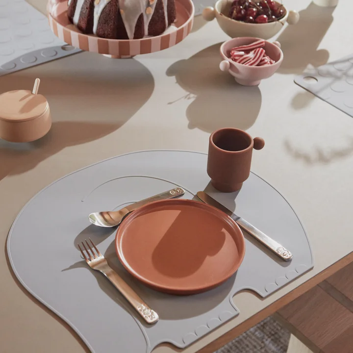 Das We Love Animals Kinder-Besteck, der Tiny Inka Silikon Becher, die Tiny Inka Silikon Schüssel und das Toppu Tablett von OYOY auf dem gedeckten Esstisch