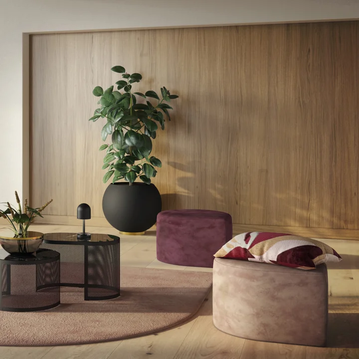 Der Globe Blumentopf von AYTM mit einer hohen Zimmerpflanze neben den Stilla Poufs von AYTM