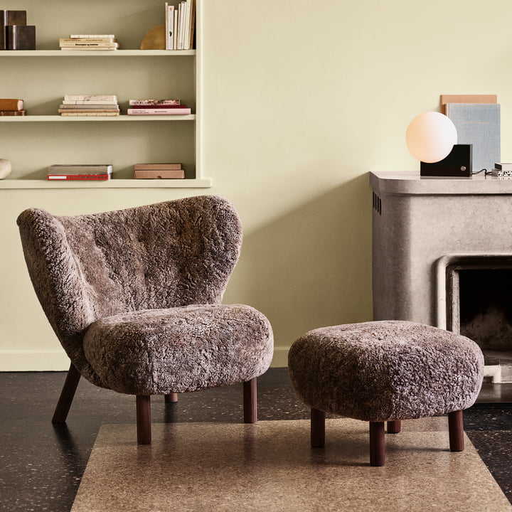 Der Little Petra Lounge Chair mit Pouf von &Tradition vor dem Steinkamin im Wohnbereich