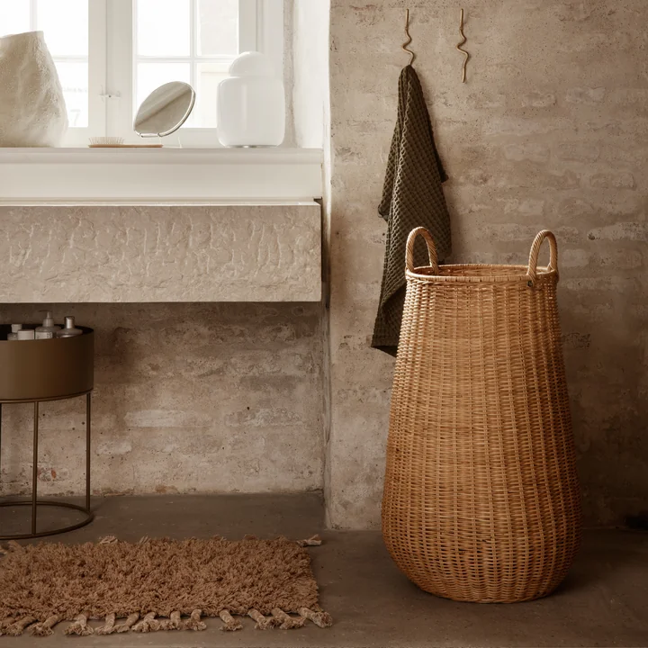 Der Amass Hochflor Fussabtreter von Ferm Living unter dem Waschbecken neben einem Rattan-Korb
