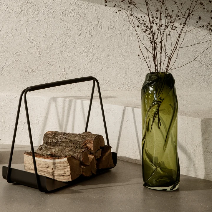Die Water Swirl Vase von Ferm Living in moosgrün auf dem Boden neben minimalistischen Kamin-Accessoires