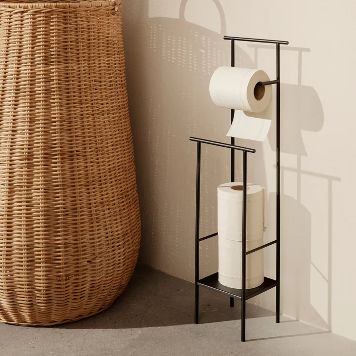 Der Dora Toilettenpapierhalter von Ferm Living neben einem grossen Rattan-Korb
