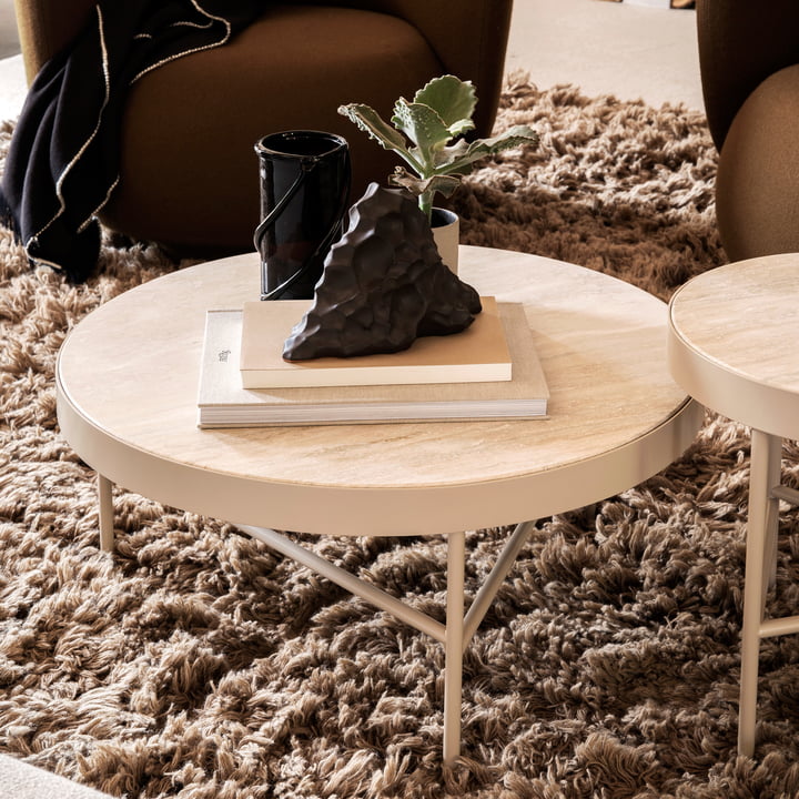 Der grosse Travertine Couchtisch von ferm Living mit Büchern und Kunstobjekten auf einem flauschigen Teppich