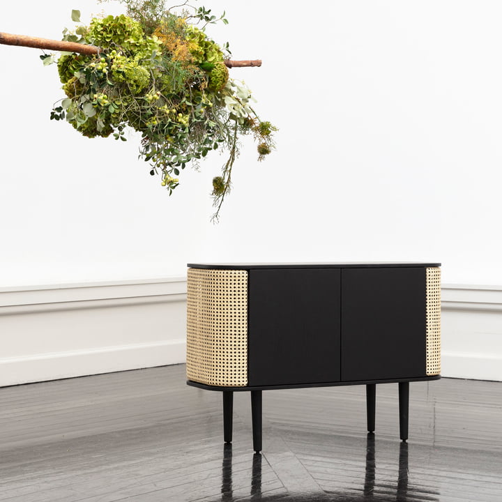 Das Treasures Sideboard von Umage in schwarz / Wiener Geflecht mit einem grünen Blumenbouquet