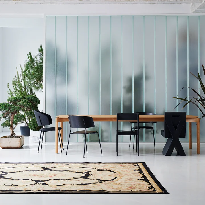 Der Wagner Dining Chair von OUT Objekte unserer Tage in anthrazit an einem grossen Holz-Esstisch neben weiteren dunklen Stühlen