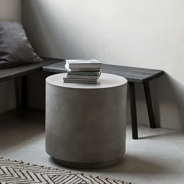 Der Out Beton Beistelltisch von House Doctor vor einer Bank im Wohnzimmer