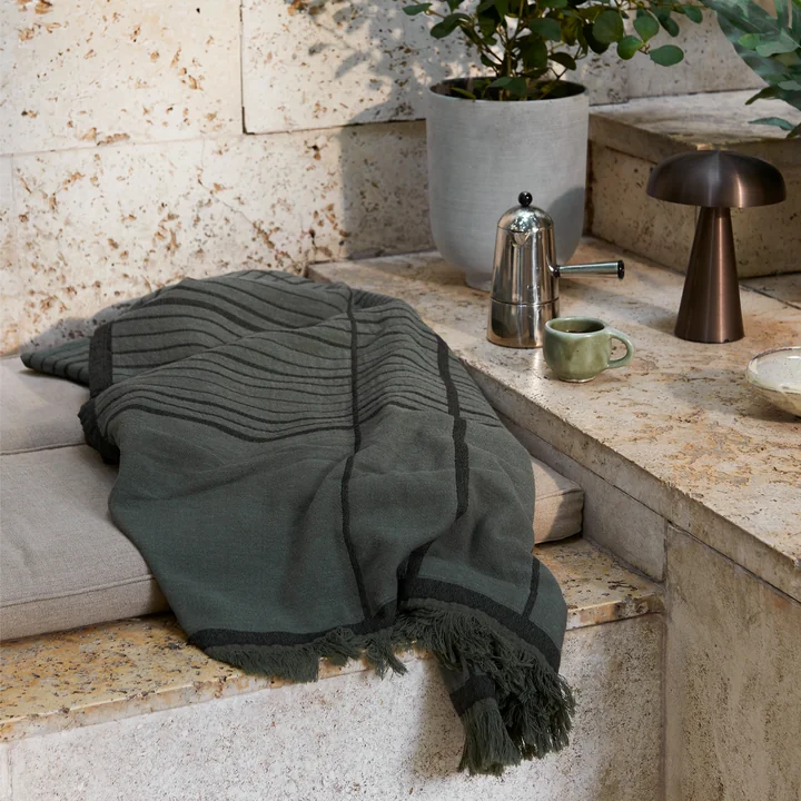 Die Untitled AP10 Tagesdecke von &Tradition auf einer Steinbank